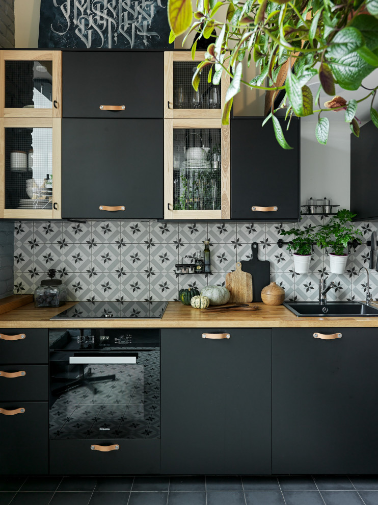 Exempel på ett mellanstort industriellt brun brunt kök, med en undermonterad diskho, släta luckor, svarta skåp, träbänkskiva, flerfärgad stänkskydd, stänkskydd i keramik, svarta vitvaror, klinkergolv i keramik och blått golv