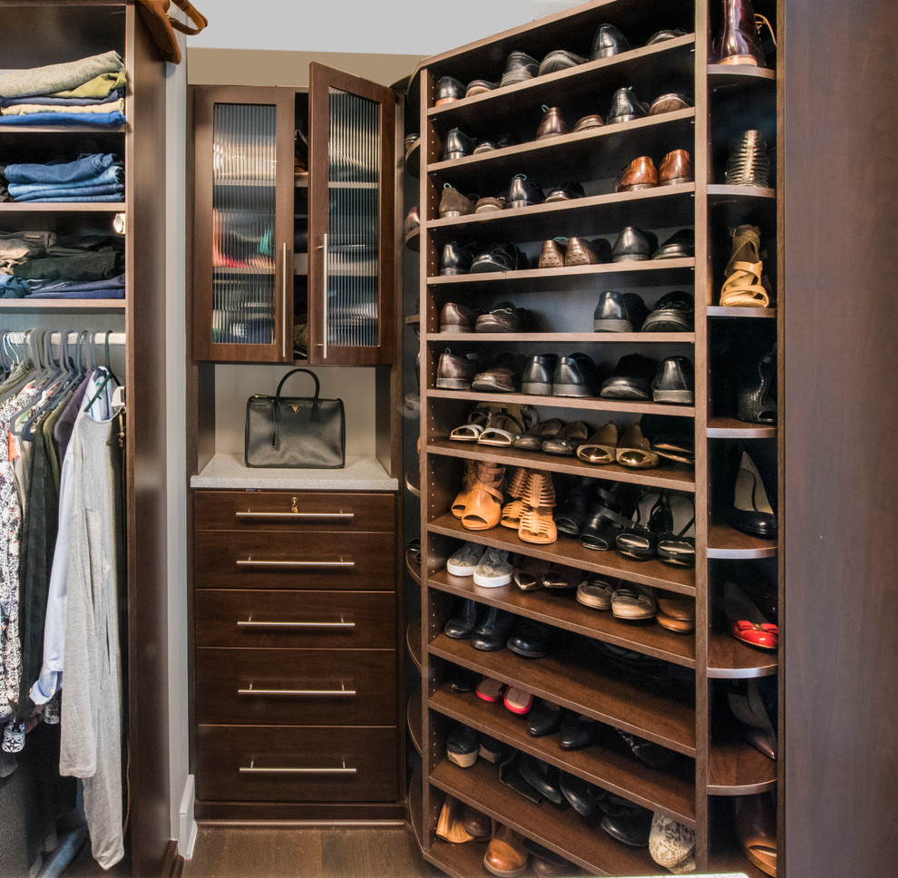 This is an example of a small modern gender-neutral walk-in wardrobe in Chicago with dark wood cabinets, dark hardwood floors and open cabinets.