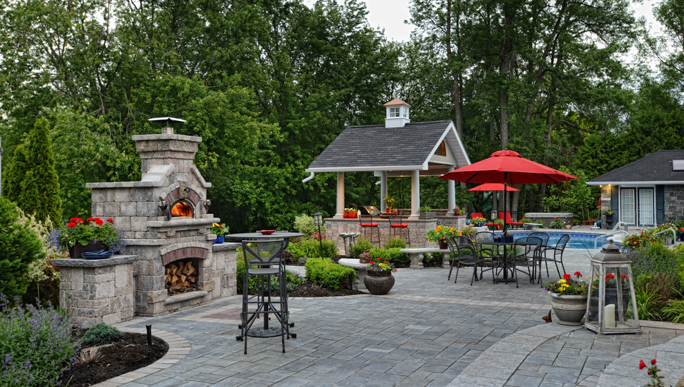 Photo of a traditional backyard patio in Toronto with a fire feature and concrete pavers.
