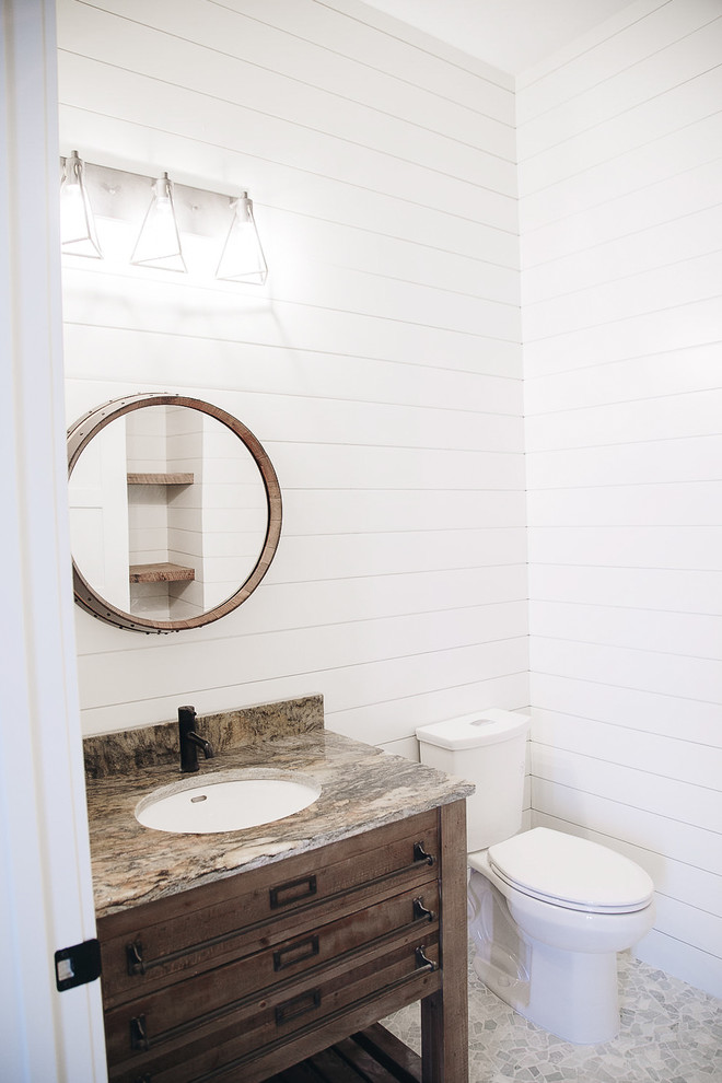 This is an example of a mid-sized country 3/4 bathroom in Minneapolis with medium wood cabinets, pebble tile floors, granite benchtops, multi-coloured benchtops, white walls, a two-piece toilet, shaker cabinets, an undermount sink and grey floor.
