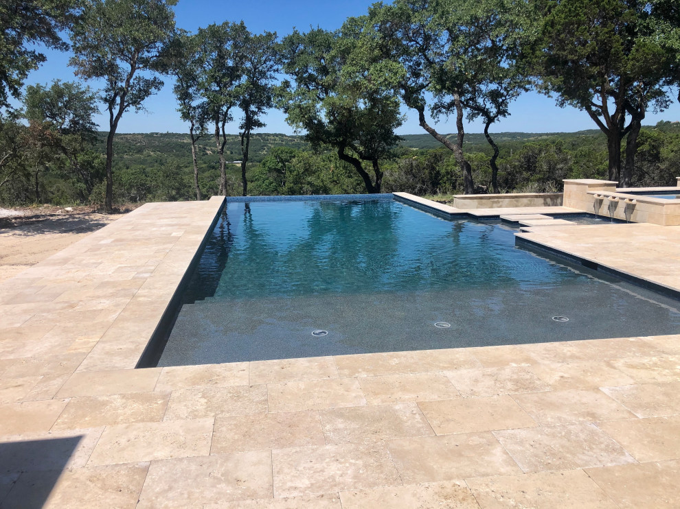 Expansive modern backyard rectangular infinity pool in Austin with a hot tub and decking.