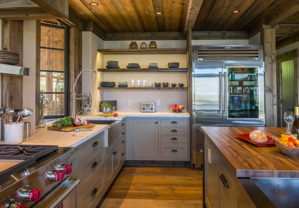 Mid-sized country l-shaped open plan kitchen in San Francisco with a farmhouse sink, recessed-panel cabinets, green cabinets, marble benchtops, stainless steel appliances, medium hardwood floors and with island.