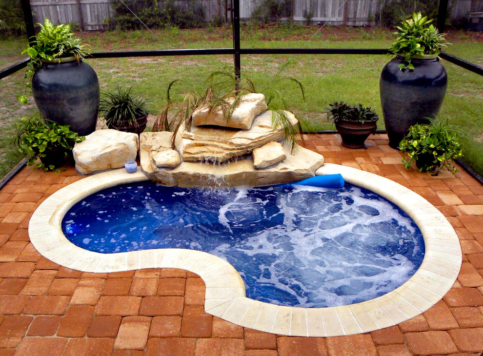 Inspiration for a small country backyard round pool in Orlando with a water feature and natural stone pavers.