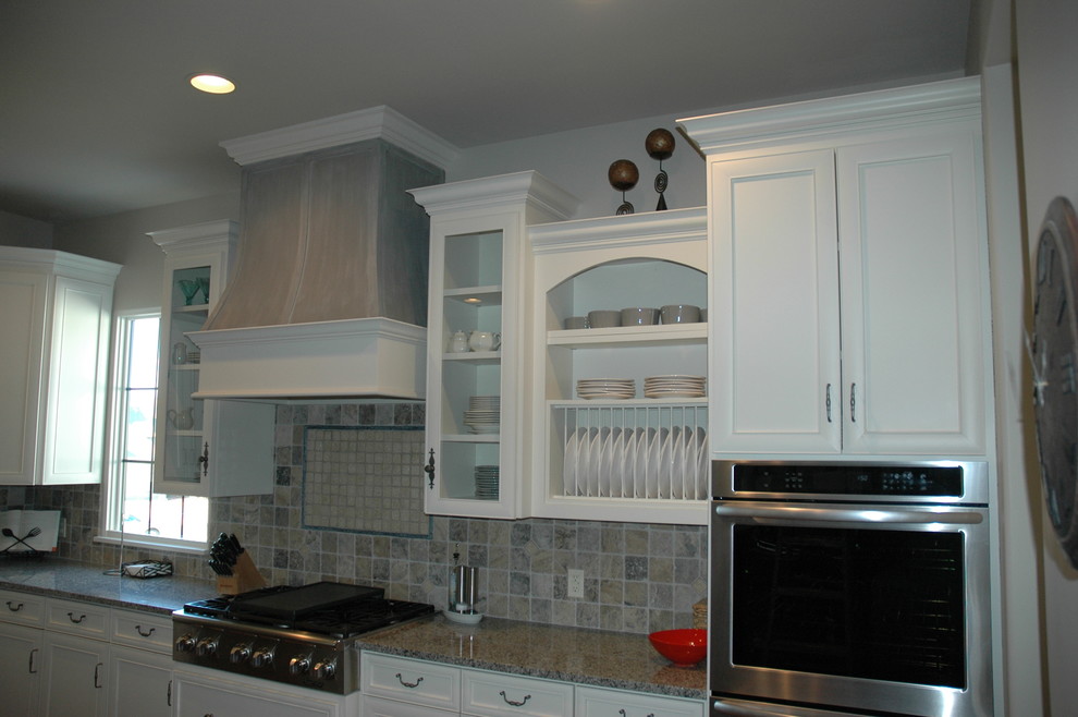 Example of a large transitional u-shaped medium tone wood floor kitchen pantry design with a farmhouse sink, flat-panel cabinets, yellow cabinets, laminate countertops, brown backsplash, stone tile backsplash, paneled appliances and an island