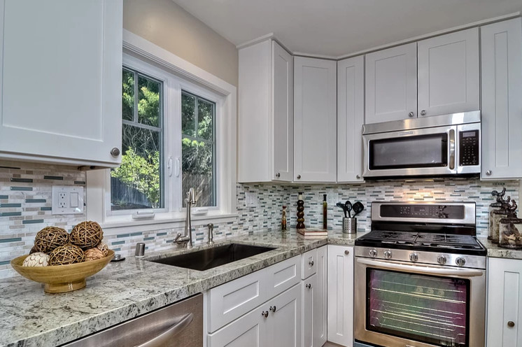 Inspiration for a mid-sized transitional l-shaped medium tone wood floor open concept kitchen remodel in Boise with an undermount sink, recessed-panel cabinets, white cabinets, granite countertops, gray backsplash, matchstick tile backsplash, stainless steel appliances and an island