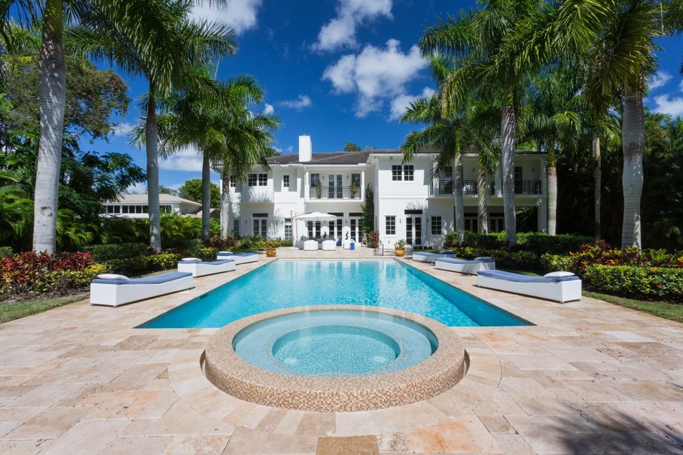 Photo of a large tropical backyard rectangular natural pool in Miami with a water feature and concrete pavers.
