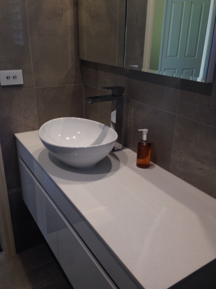 This is an example of a small contemporary bathroom in Geelong with a vessel sink, white cabinets, a curbless shower, a two-piece toilet, beige tile and beige walls.