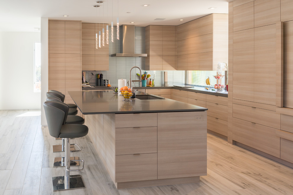 Contemporary l-shaped kitchen in Other with an undermount sink, flat-panel cabinets, light wood cabinets, grey splashback, with island, beige floor, grey benchtop, glass tile splashback and ceramic floors.