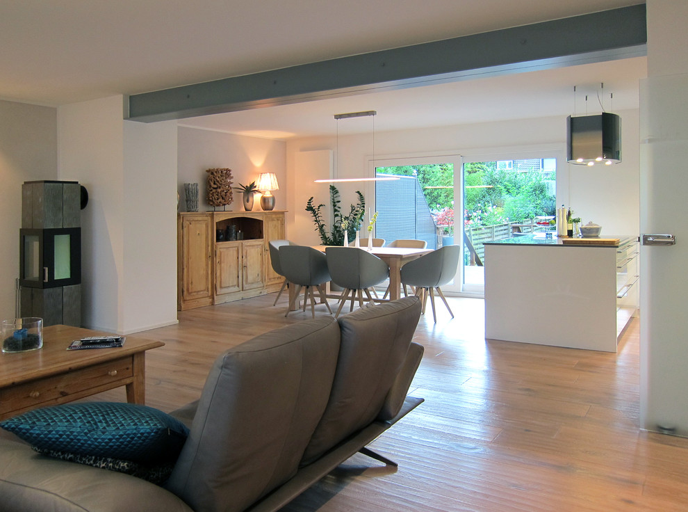 Cette image montre un salon design de taille moyenne et ouvert avec un mur gris, parquet clair et un poêle à bois.