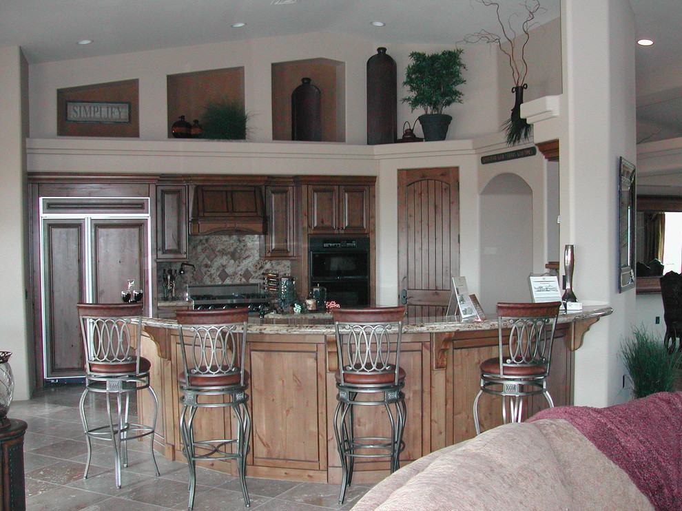Kitchen - transitional u-shaped travertine floor kitchen idea in Phoenix with raised-panel cabinets, dark wood cabinets, granite countertops, beige backsplash, stone tile backsplash, paneled appliances and an island