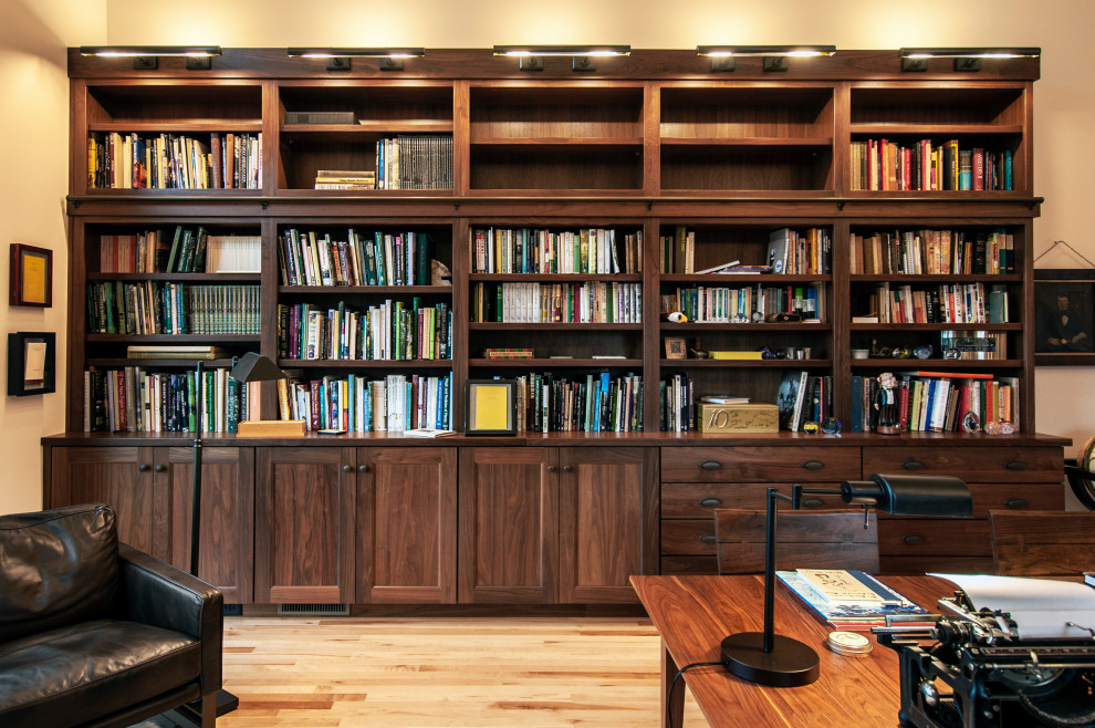 Photo of a large arts and crafts home office in Nashville with a library, white walls, light hardwood floors, a built-in desk, brown floor and vaulted.