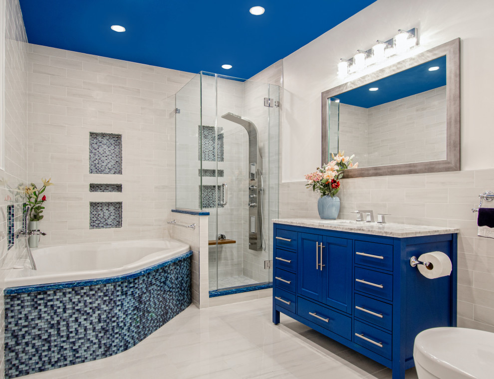 Exemple d'une salle de bain principale moderne de taille moyenne avec un placard à porte shaker, des portes de placard bleues, une baignoire posée, une douche d'angle, WC à poser, un carrelage beige, des carreaux de porcelaine, un mur beige, un sol en carrelage de céramique, un lavabo encastré, un plan de toilette en quartz modifié, un sol beige, une cabine de douche à porte battante, un plan de toilette beige, un banc de douche, meuble simple vasque, meuble-lavabo sur pied et un plafond décaissé.