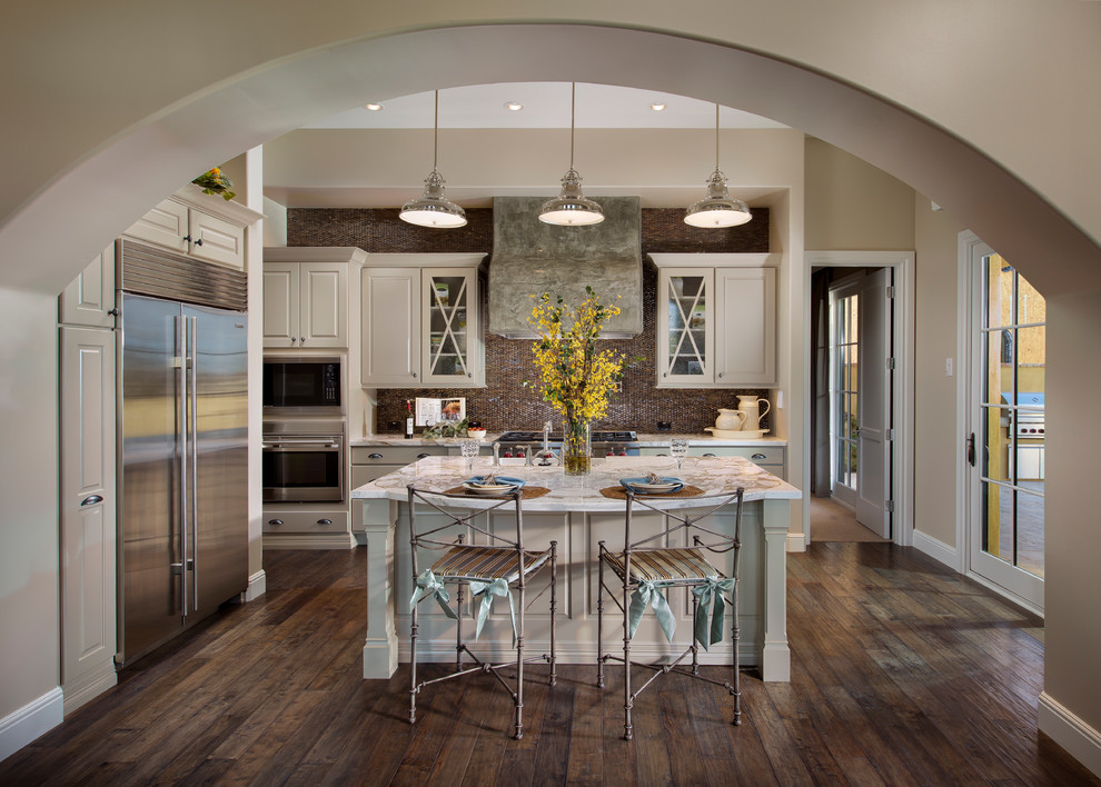 Kitchen - transitional galley brown floor kitchen idea in Phoenix with raised-panel cabinets, white cabinets, brown backsplash and stainless steel appliances