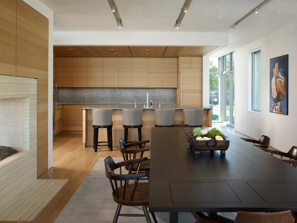 Photo of a contemporary eat-in kitchen in Chicago with flat-panel cabinets, light wood cabinets, grey splashback, an undermount sink, panelled appliances, light hardwood floors and with island.