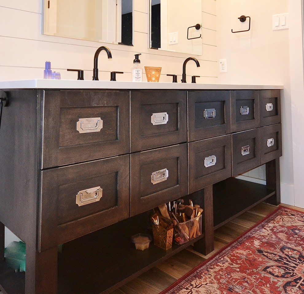 This is an example of a large transitional master bathroom in Philadelphia with shaker cabinets, distressed cabinets, a freestanding tub, a double shower, a one-piece toilet, multi-coloured tile, subway tile, white walls, medium hardwood floors, an undermount sink, engineered quartz benchtops, brown floor, a hinged shower door and white benchtops.