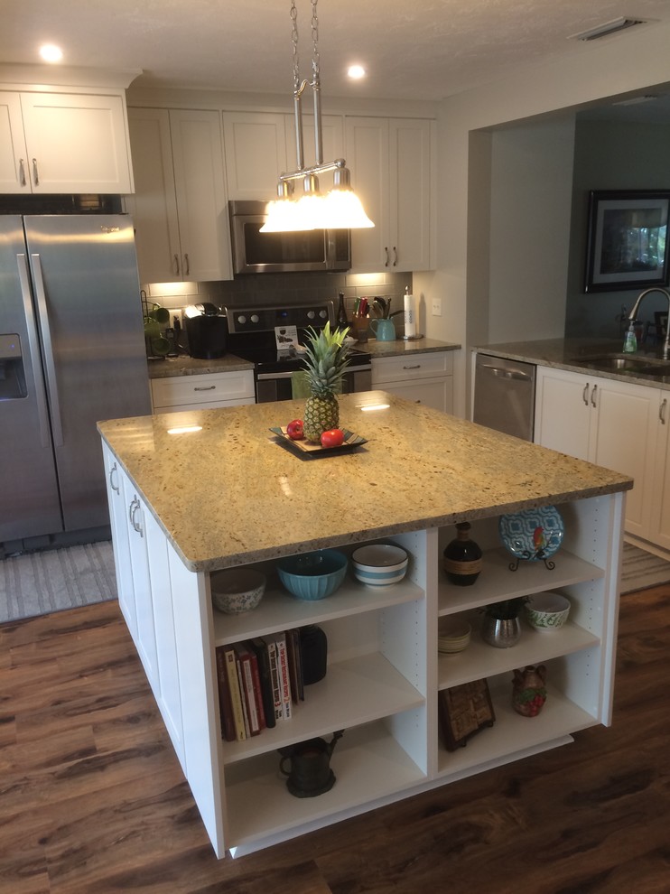 Photo of a mid-sized traditional l-shaped separate kitchen in Tampa with an undermount sink, raised-panel cabinets, white cabinets, granite benchtops, grey splashback, subway tile splashback, stainless steel appliances, medium hardwood floors and with island.