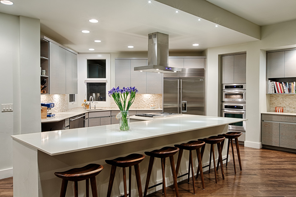 Mid-sized contemporary l-shaped eat-in kitchen in Denver with an undermount sink, flat-panel cabinets, white cabinets, solid surface benchtops, beige splashback, stone tile splashback, stainless steel appliances, dark hardwood floors and with island.
