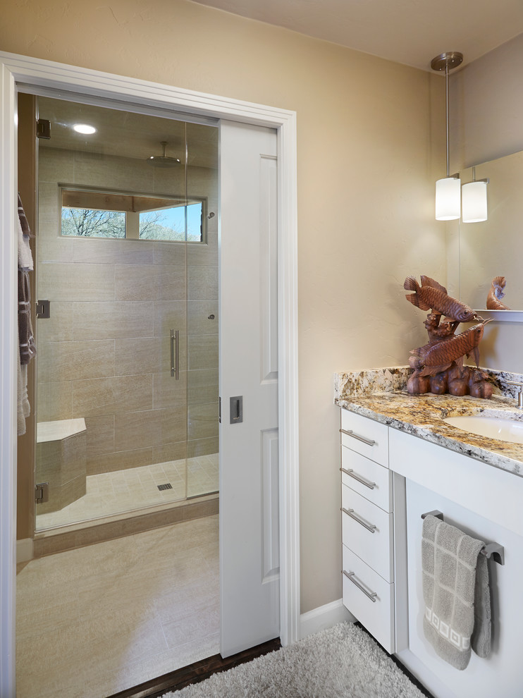 Inspiration for a transitional bathroom in Phoenix with flat-panel cabinets, white cabinets, granite benchtops, an alcove shower, beige tile, porcelain tile, an undermount sink, a two-piece toilet, beige walls and porcelain floors.