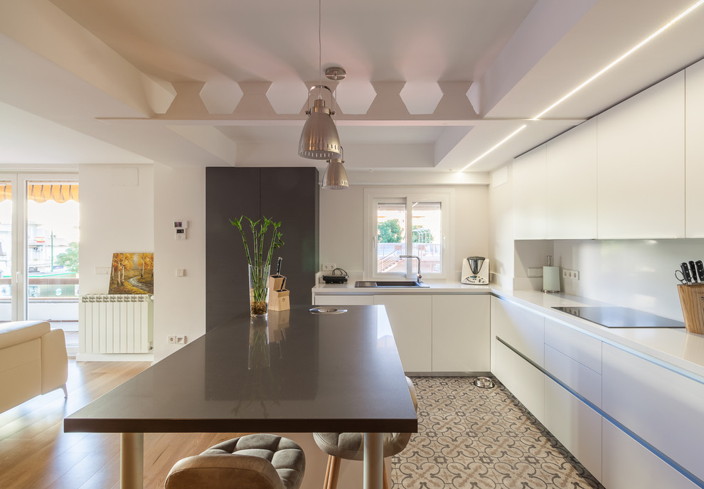 Mid-sized contemporary l-shaped open plan kitchen in Seville with flat-panel cabinets, white cabinets, white splashback, panelled appliances, ceramic floors, with island, multi-coloured floor and a single-bowl sink.