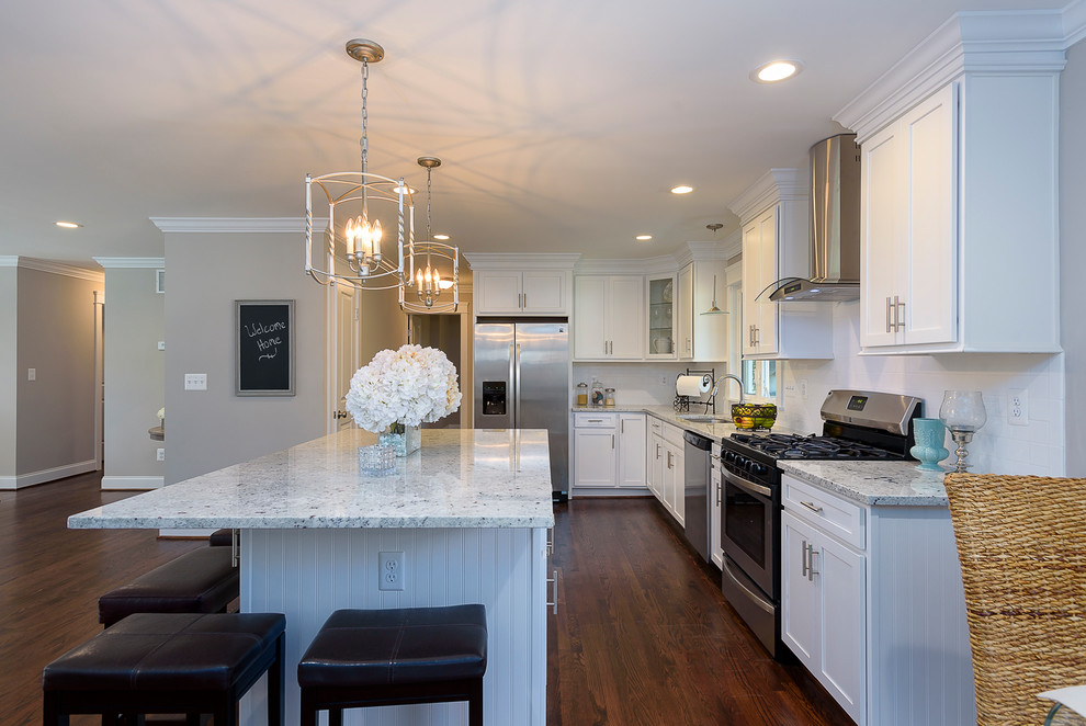 Eat-in kitchen - large transitional l-shaped medium tone wood floor and brown floor eat-in kitchen idea in Baltimore with an undermount sink, shaker cabinets, white cabinets, granite countertops, white backsplash, ceramic backsplash, stainless steel appliances and an island