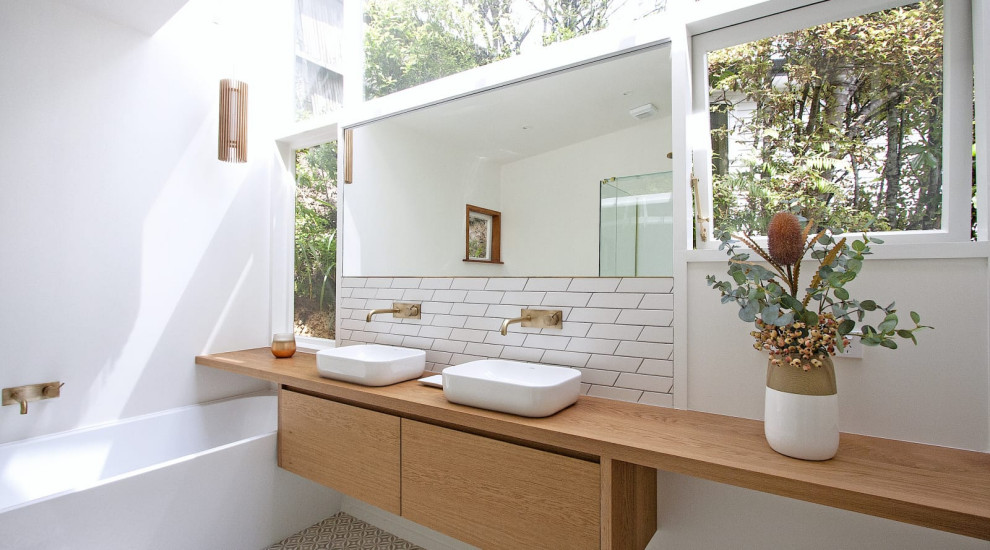 Design ideas for a mid-sized scandinavian kids bathroom in Perth with furniture-like cabinets, medium wood cabinets, a freestanding tub, a corner shower, white tile, ceramic tile, white walls, porcelain floors, a vessel sink, wood benchtops, multi-coloured floor, a hinged shower door, a double vanity, a floating vanity and timber.