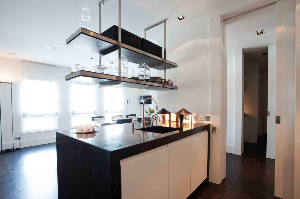 This is an example of a mid-sized contemporary l-shaped eat-in kitchen in New York with an undermount sink, flat-panel cabinets, white cabinets, solid surface benchtops, black splashback, stainless steel appliances and a peninsula.