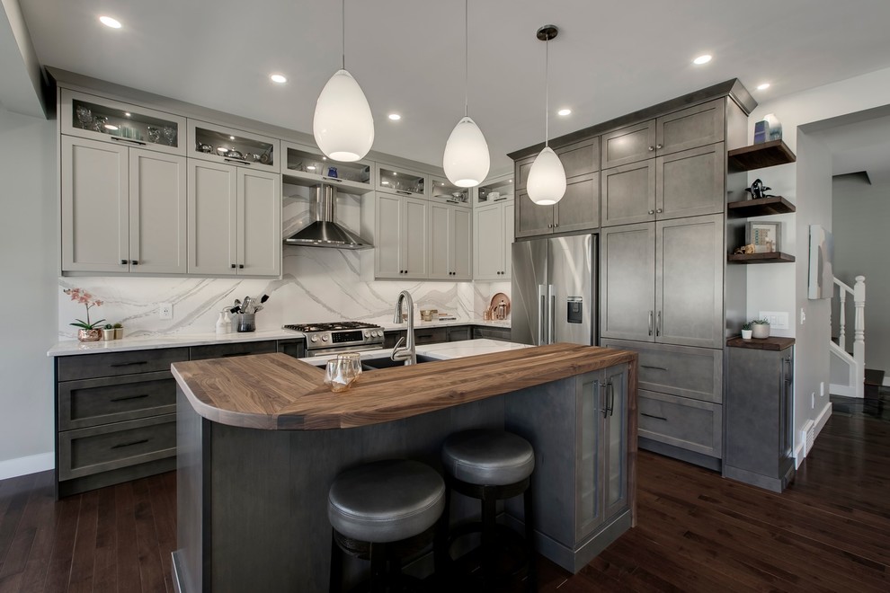 Eat-in kitchen - large transitional u-shaped dark wood floor and brown floor eat-in kitchen idea in Calgary with an undermount sink, recessed-panel cabinets, gray cabinets, quartzite countertops, white backsplash, stone slab backsplash, stainless steel appliances, an island and white countertops