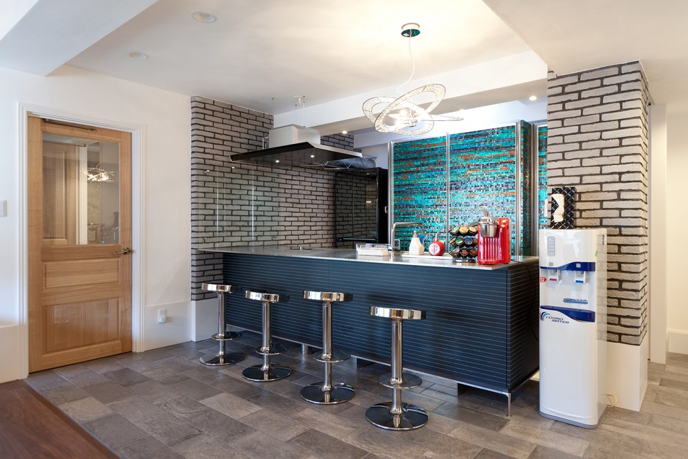 Modern single-wall kitchen with an integrated sink, grey cabinets, stainless steel benchtops, grey splashback, stainless steel appliances, marble floors, with island, grey floor and grey benchtop.
