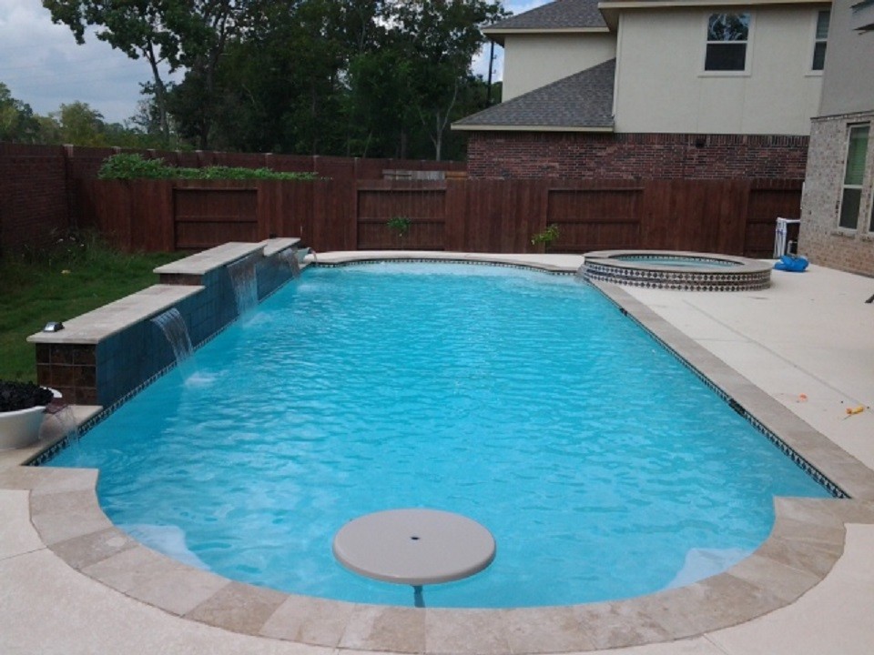Large contemporary backyard custom-shaped lap pool in Houston with a water feature and concrete slab.