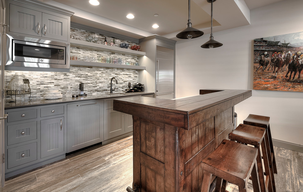 Design ideas for a large transitional l-shaped seated home bar in Seattle with an undermount sink, grey cabinets, multi-coloured splashback, matchstick tile splashback, dark hardwood floors, beaded inset cabinets, quartzite benchtops, grey floor and grey benchtop.