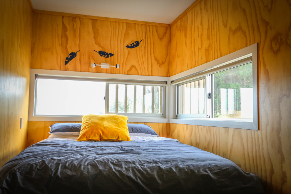 This is an example of a small beach style loft-style bedroom in Napier-Hastings with yellow walls, painted wood floors and brown floor.