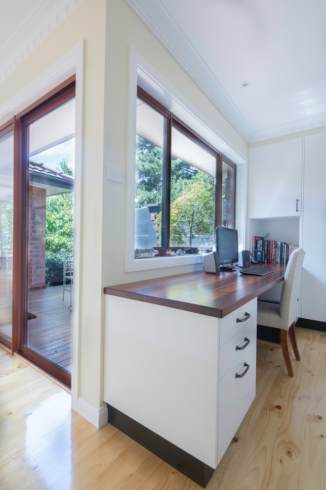 Photo of a small contemporary study room in Canberra - Queanbeyan with beige walls, light hardwood floors, a built-in desk and brown floor.