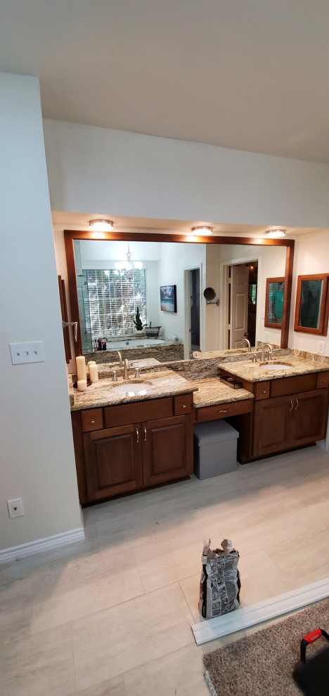 Large traditional master bathroom in Dallas with raised-panel cabinets, brown cabinets, an undermount tub, a corner shower, a one-piece toilet, multi-coloured tile, glass tile, beige walls, porcelain floors, an undermount sink, granite benchtops, multi-coloured floor, a hinged shower door, multi-coloured benchtops, a shower seat, a double vanity, a built-in vanity and wallpaper.
