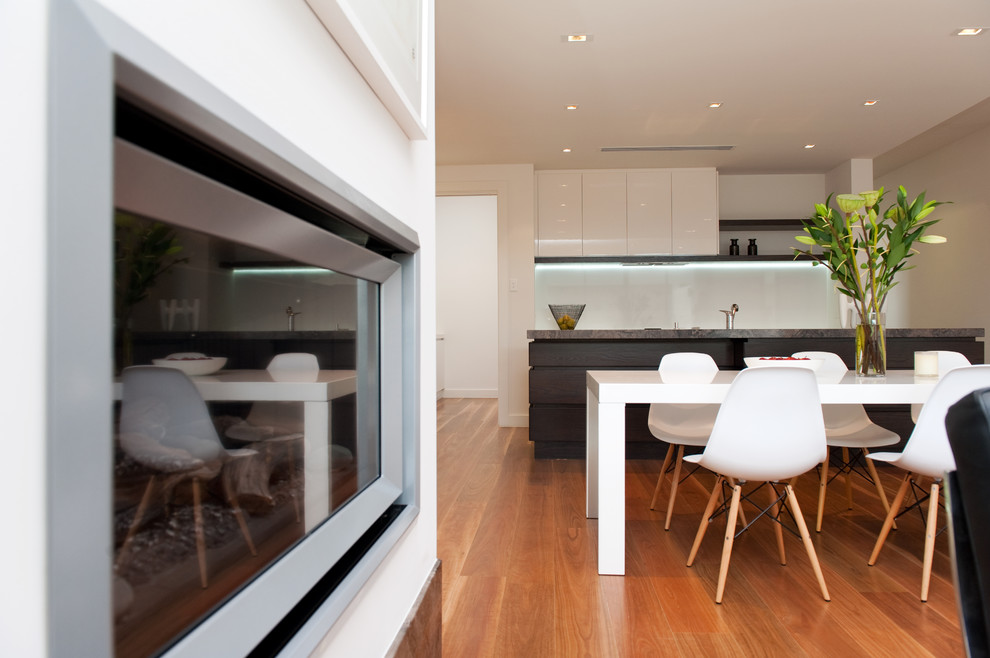 Photo of a mid-sized contemporary eat-in kitchen in Adelaide with a double-bowl sink, flat-panel cabinets, dark wood cabinets, limestone benchtops, white splashback, stainless steel appliances and with island.