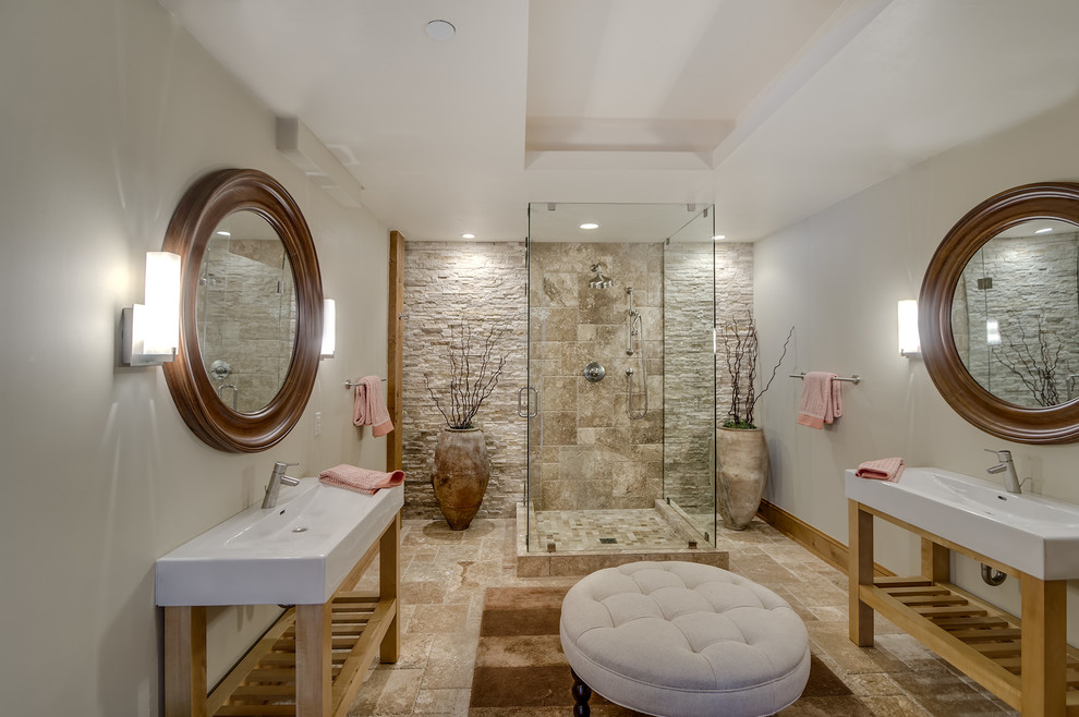 Large mountain style master beige tile and stone tile travertine floor and brown floor bathroom photo with open cabinets, beige walls, an integrated sink, solid surface countertops and a hinged shower door