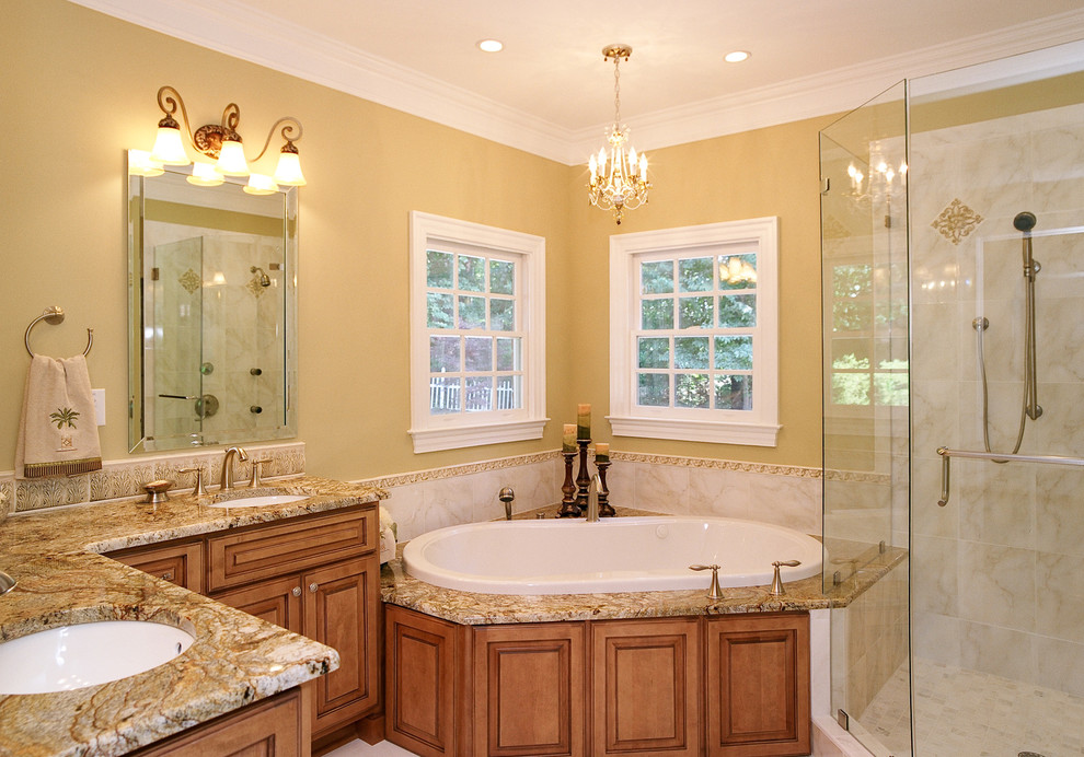 This is an example of a large traditional master bathroom in Other with an undermount sink, raised-panel cabinets, medium wood cabinets, granite benchtops, a drop-in tub, a corner shower, a two-piece toilet, multi-coloured tile, porcelain tile, yellow walls and porcelain floors.