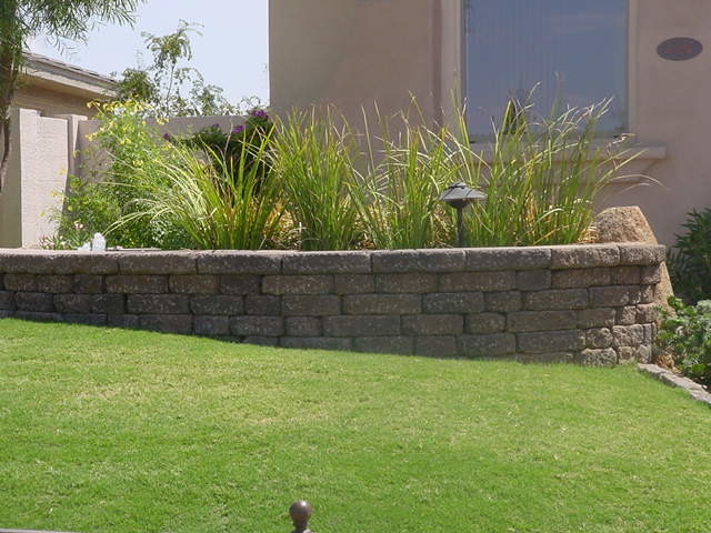 Photo of a mid-sized front yard full sun garden for summer in Phoenix with a retaining wall and brick pavers.