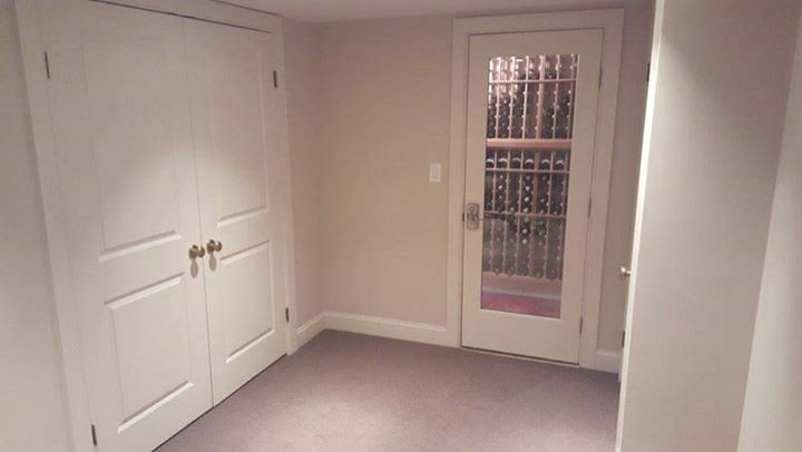 Basement - mid-sized transitional underground carpeted and beige floor basement idea with black walls, a standard fireplace and a brick fireplace