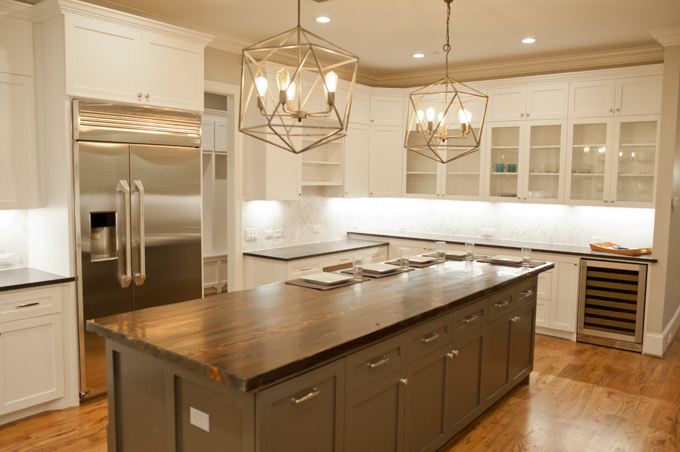 This is an example of an expansive transitional u-shaped kitchen in Houston with shaker cabinets, white cabinets, wood benchtops and with island.