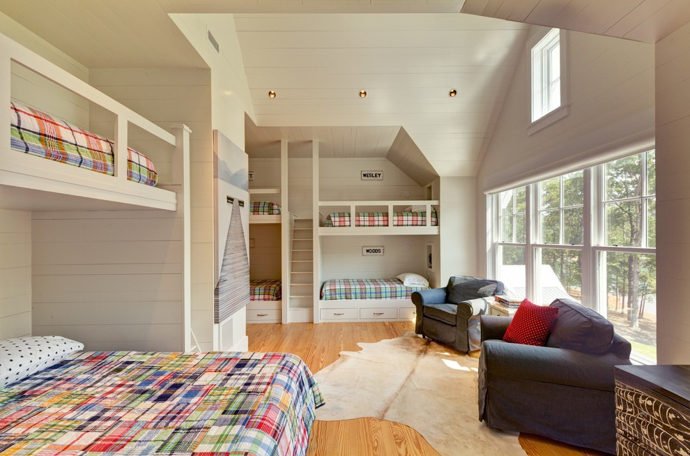 This is an example of a country gender-neutral kids' bedroom for kids 4-10 years old in Other with white walls and light hardwood floors.