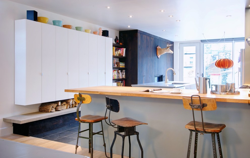 Contemporary l-shaped kitchen in Toronto with flat-panel cabinets, white cabinets and wood benchtops.