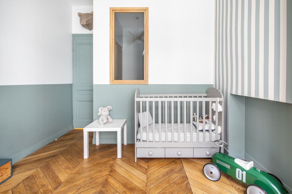 Foto de habitación de bebé neutra vintage pequeña con paredes azules, suelo de madera clara, suelo marrón y papel pintado