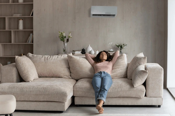 woman relaxing on sofa while air conditioning is blowing in the back