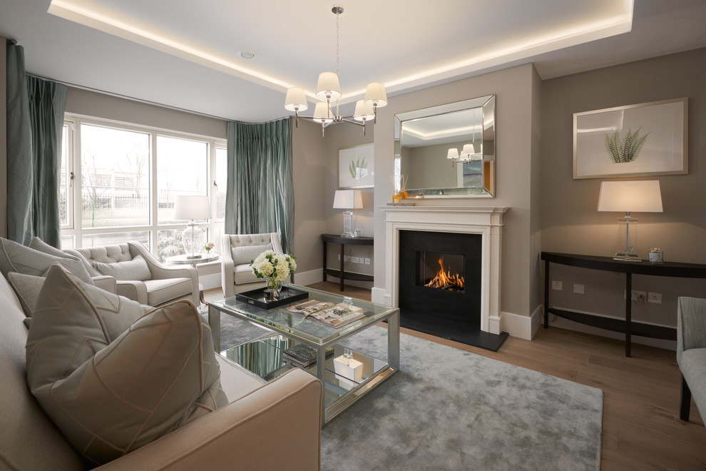This is an example of a transitional formal enclosed living room in Dublin with beige walls, medium hardwood floors, a standard fireplace, a metal fireplace surround, no tv and brown floor.