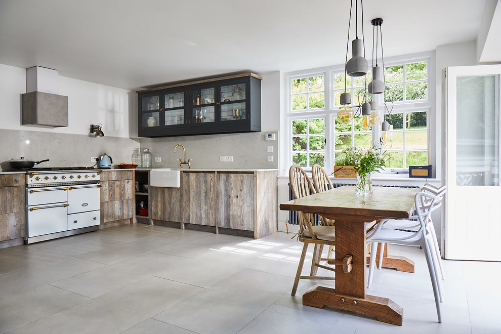 Design ideas for a mid-sized l-shaped eat-in kitchen in Other with a farmhouse sink, flat-panel cabinets, light wood cabinets, grey splashback, white appliances, no island, grey floor and white benchtop.