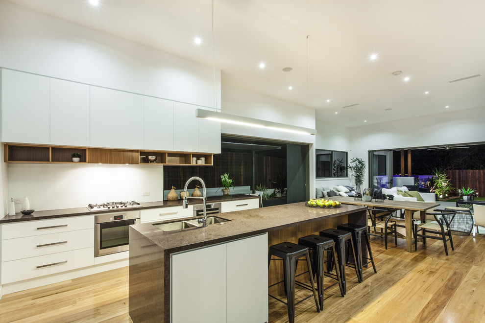 Large trendy single-wall dark wood floor and brown floor eat-in kitchen photo with a double-bowl sink, flat-panel cabinets, white cabinets, quartz countertops and an island