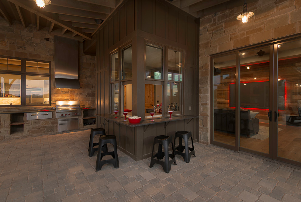 Design ideas for a country backyard patio in Austin with an outdoor kitchen, natural stone pavers and a roof extension.
