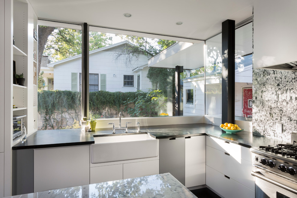 Modern kitchen in Austin with a farmhouse sink, flat-panel cabinets, white cabinets and stainless steel appliances.
