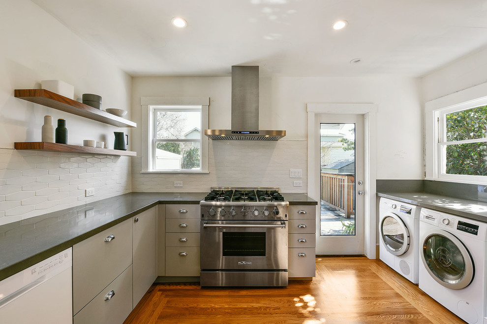 Inspiration for a mid-sized transitional galley light wood floor and beige floor enclosed kitchen remodel in San Francisco with flat-panel cabinets, beige cabinets, quartz countertops, white backsplash, ceramic backsplash, stainless steel appliances and no island