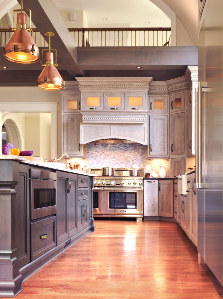 Inspiration for a large transitional l-shaped medium tone wood floor eat-in kitchen remodel in DC Metro with a farmhouse sink, beaded inset cabinets, gray cabinets, granite countertops, gray backsplash, glass tile backsplash, stainless steel appliances and an island